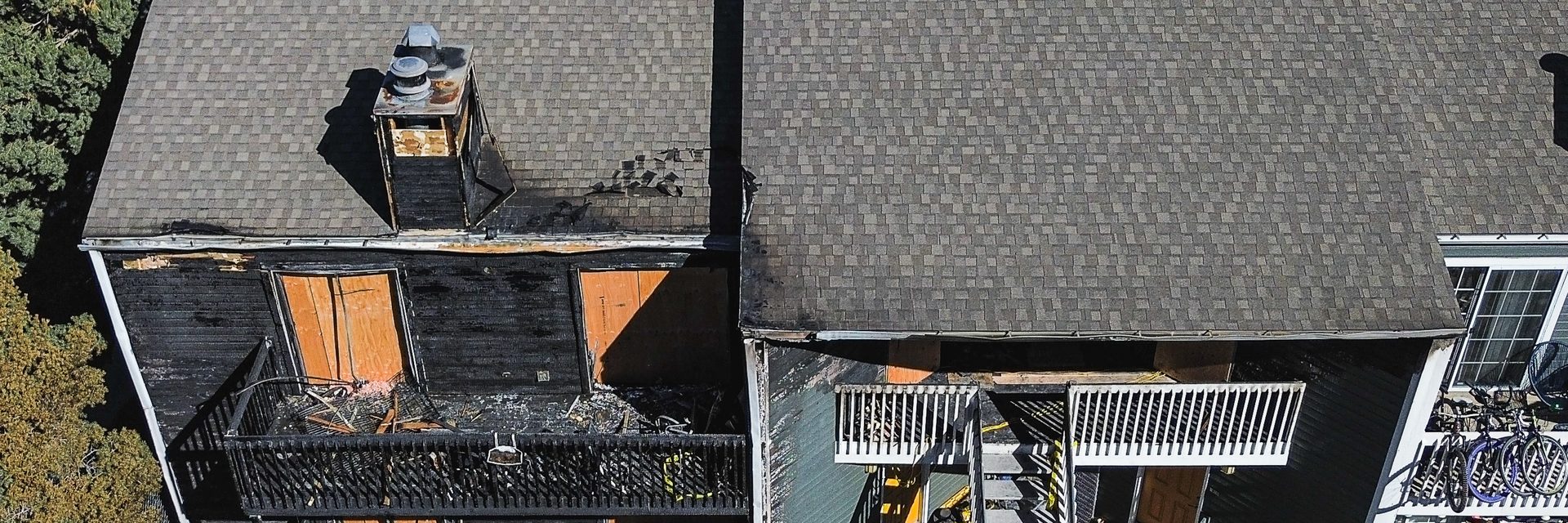 Fire-damaged apartment building with charred siding and balconies across two storeys