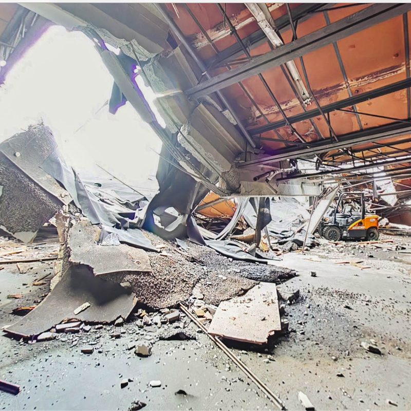 Collapsed roof structure and debris across the warehouse floor