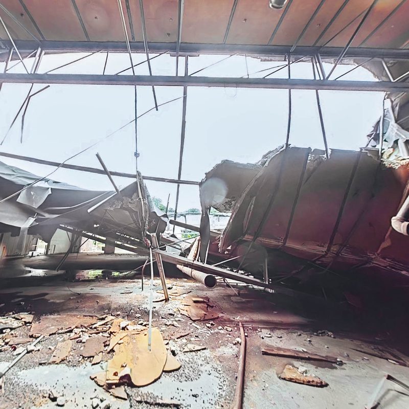Failed roof decking hanging from the steel frame above the debris field