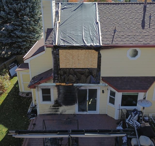 Wider aerial of the damaged elevation and the tarped roof section
