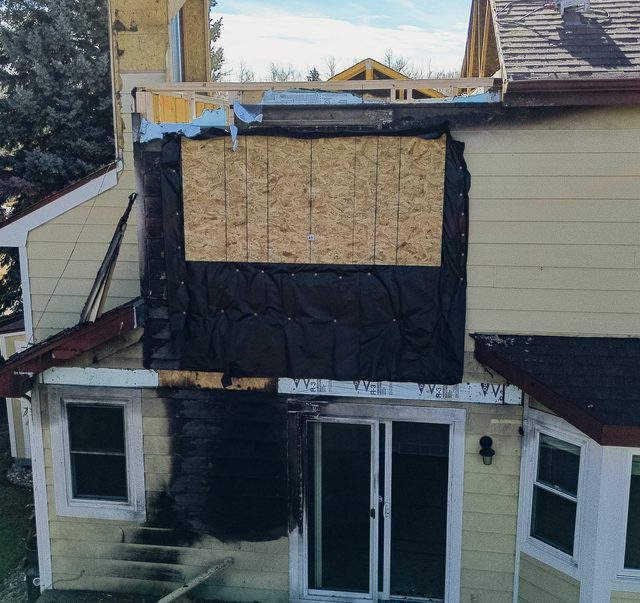 Black house wrap and a boarded opening above the patio doors