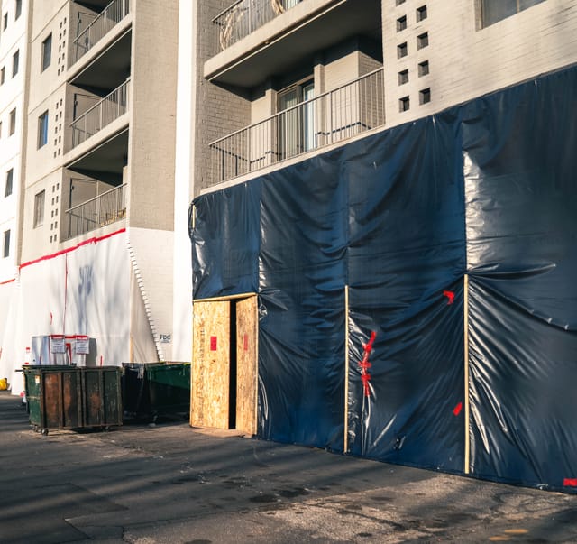 Sheeting closing off the ground-floor parking openings along the block