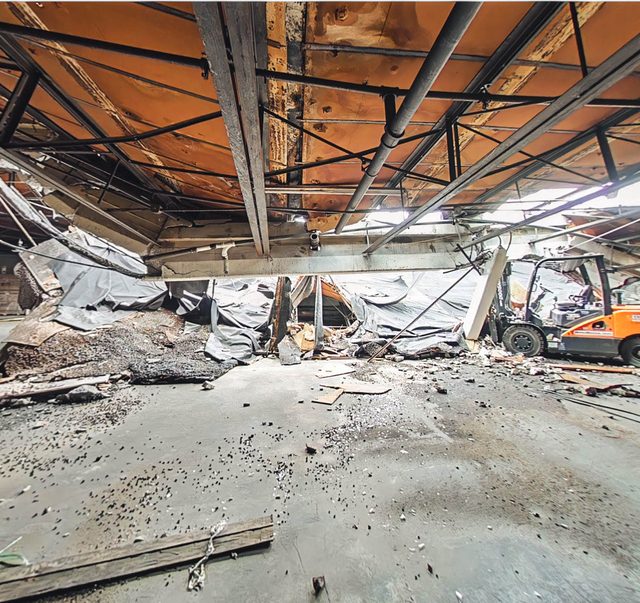 Collapsed roof section and debris across the warehouse floor